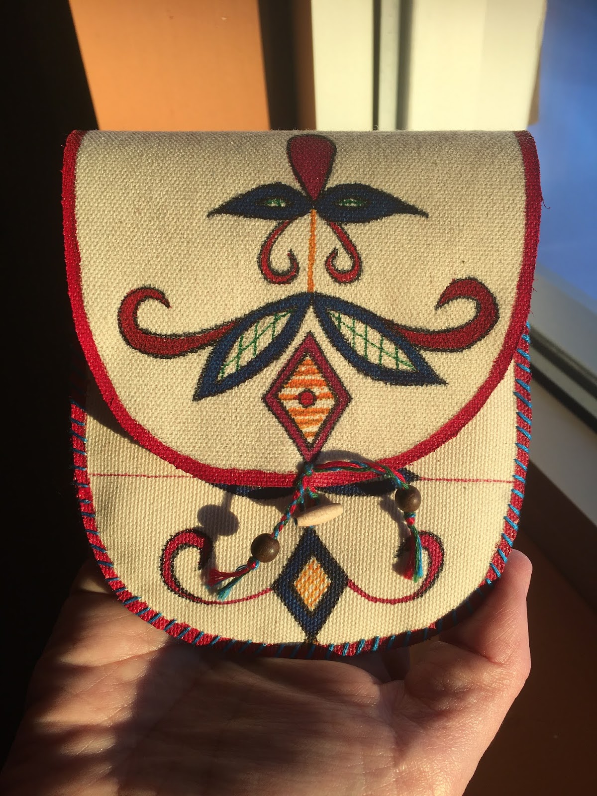 This is a small purse made by Trifona Simard. She decided to paint on canvas, as she wanted to explore her talent before committing to painting on caribou-skin. Before she painted on the canvas, she practiced painting designs on paper until she gained confidence in handling the paint and the tools.